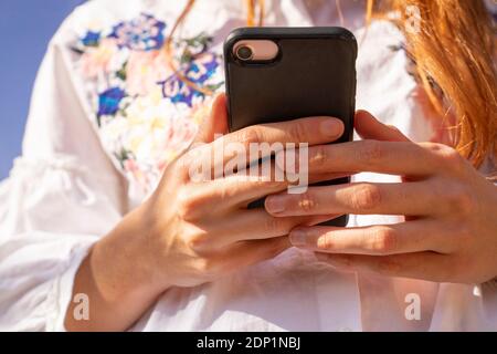 Giovane donna che utilizza la messaggistica di testo tramite smartphone Foto Stock