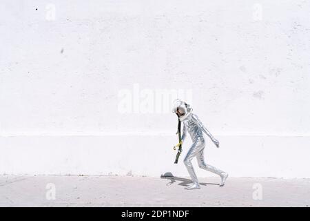 Ragazzo che indossa un costume astronauta che corre contro il muro in città Foto Stock