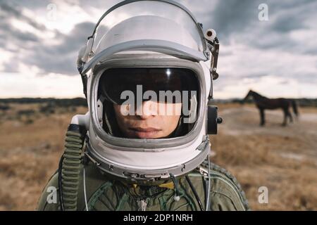 Ponendo l'uomo vestito come un astronauta su un prato con drammatica nuvole in background Foto Stock