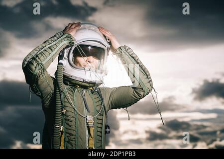 Ponendo l'uomo vestito come un astronauta con drammatica nuvole in background Foto Stock