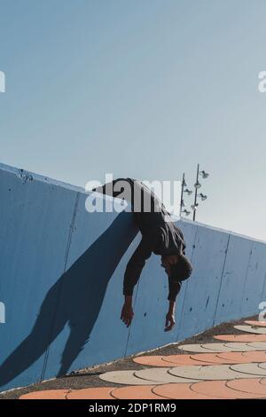 Giovane uomo che indossa kaftan nero sdraiato su muro blu Foto Stock