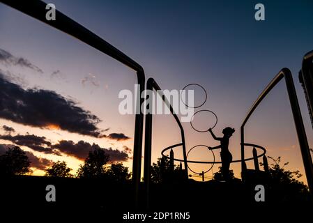 Silhouette donna sportiva che giocola i cerchi in plastica contro il cielo durante il tramonto Foto Stock