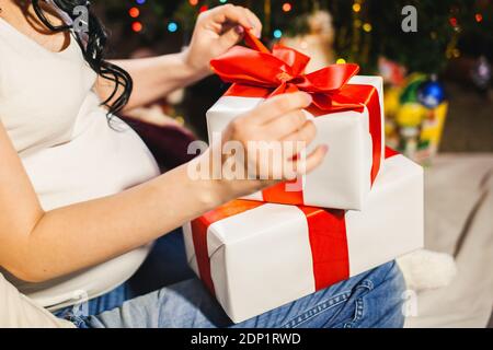 donna incinta che disimballa scatola di natale Foto Stock