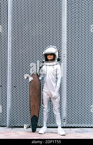 Bambino vestito come un astronauta con longboard Foto Stock