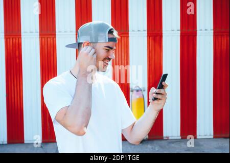Sorridente giovane uomo utilizza lo smartphone nella città Foto Stock