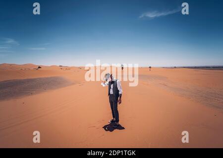 Uomo con la barba e hat nelle dune del deserto del Marocco Foto Stock