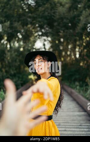 Giovane donna che indossa un cappello nero e giallo il vestito e tenendo una mano Foto Stock