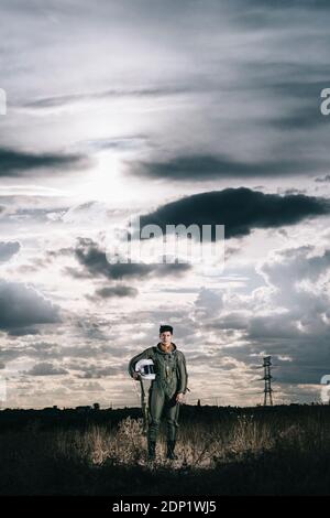 Ponendo l'uomo vestito come un astronauta su un prato con drammatica nuvole in background Foto Stock