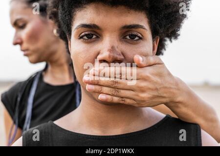 Donna di mano che copre la bocca di un'altra donna, close-up Foto Stock