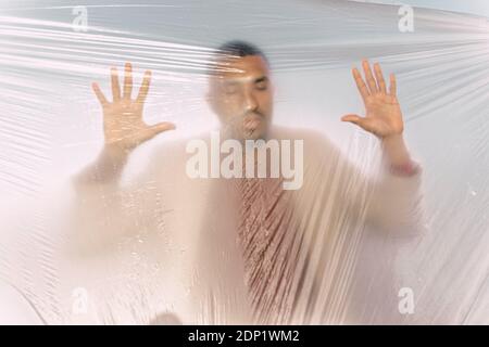 Uomo intrappolato in un foglio di plastica Foto Stock