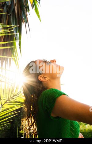 Donna sotto palme che gode del sole Foto Stock
