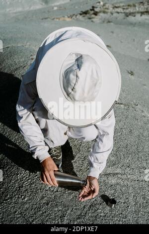 Uomo con matraccio thermos che indossa un abito da guardiano in un paesaggio arido Foto Stock