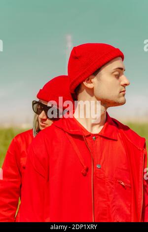 Giovane coppia con occhi chiusi vestita di rosso all'aperto Foto Stock