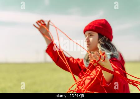 Giovane donna vestita di rosso che si esibisce con una corda rossa all'aperto Foto Stock