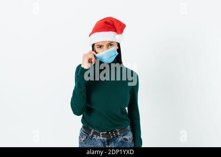 Triste giovane donna in maschera medica e cappello di santa sfondo bianco Foto Stock