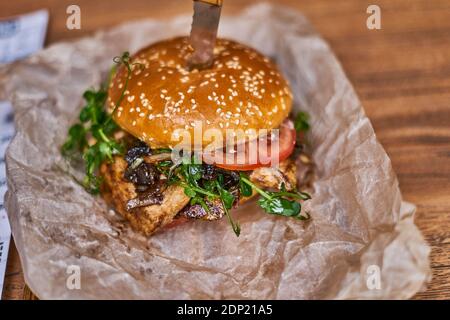 Delizioso hamburger di pollo su carta e tavola di legno Foto Stock