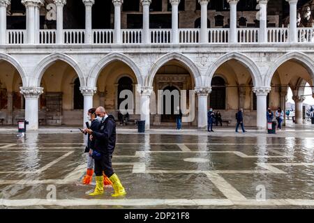 Visitors Wearing Water Protective Plastic Shoe Covers In St Mark’s Square During Acqua Alta (High Tide), Venice, Italy. Stock Photo