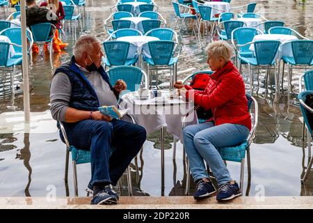 Due persone che bevono caffè in un caffè in Piazza San Marco durante l'acqua alta (alta marea), Venezia, Italia. Foto Stock