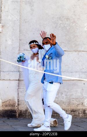 Una coppia appena sposata sventolando a Wellwishers, Venezia, Italia. Foto Stock