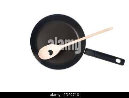 Spatola in legno per cucinare con cuore tagliato in padella antiaderente isolata su sfondo bianco. Vista dall'alto Foto Stock