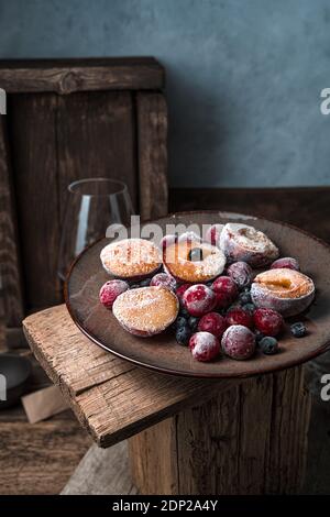 Ancora vita con frutti di bosco e frutti surgelati in un piatto marrone su sfondo vintage. Foto Stock