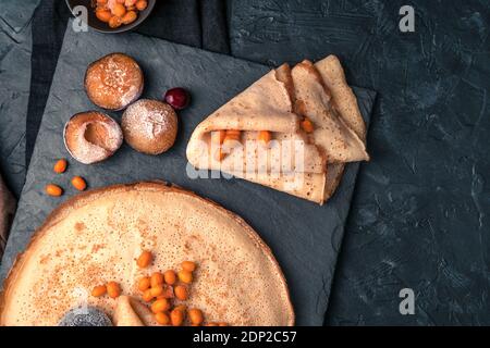 Frittelle con frutti di bosco surgelati su sfondo nero testurizzato. Vista dall'alto, con spazio per la copia. Foto Stock