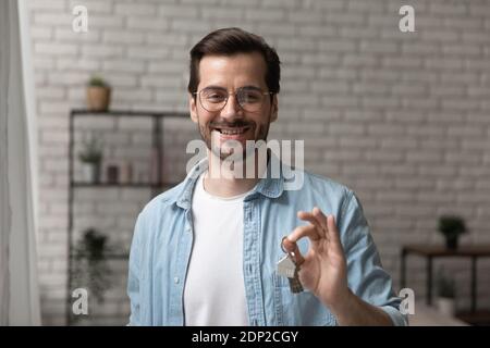 Amichevole uomo broker in posa con le chiavi di appartamento per la vendita Foto Stock