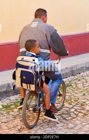 Padre che porta il bambino a scuola in bicicletta, Trinidad, Cuba Foto Stock
