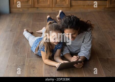 Felice bambina e mamma che usano l'app Education sul tablet Foto Stock