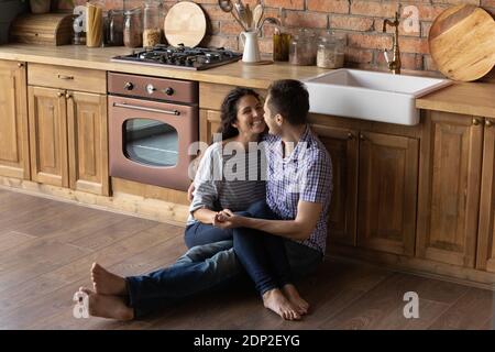 Il marito amorevole siede sul pavimento caldo che tiene la moglie sulle ginocchia Foto Stock