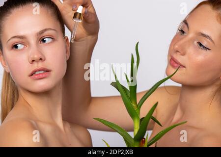 Ragazze con pelle pulita e idratata. Siero e aloe vera fiore. Concetto di bellezza, benessere e salute, su sfondo bianco Foto Stock