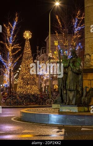 La piazza e la rotonda con i 4 vescovi che guardano le decorazioni natalizie e il gigantesco albero illuminato di wyck, Maastricht. Foto Stock