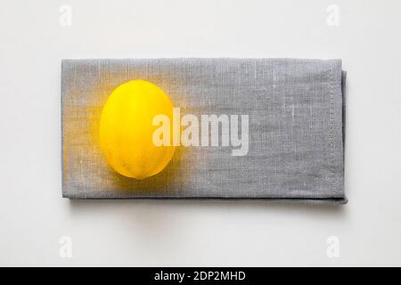 Il concetto creativo di Colour of the Year 2021. Giallo limone illuminante su tovagliolo di lino grigio Foto Stock