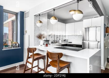 Una nuova, moderna cucina completamente bianca con luci nere appese al  soffitto e sgabelli da bar neri che si siedono al banco per un'area da  pranzo Foto stock - Alamy