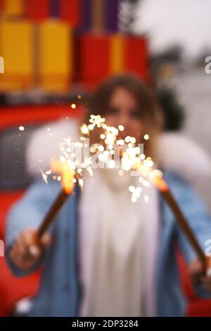 Le mani femminili stanno tenendo sparklers brucianti. Donna all'aperto in inverno Foto Stock