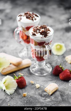 Dessert di frutti di bosco sani. Trifle di fragole con fragole, panna montata e bisquit in bicchieri fuoco selettivo Foto Stock