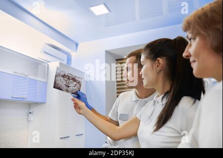 Un team di dentisti che esaminano i raggi X orali nell'ufficio odontoiatrico. Odontoiatria Foto Stock