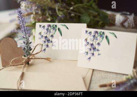 cartoncini per la scrittura di nomi vuoti, busta sul tavolo con fiore di lavanda Foto Stock