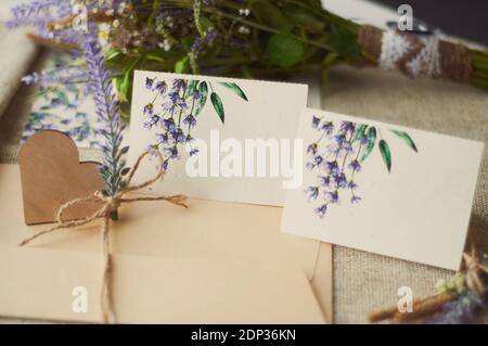 cartoncini per la scrittura di nomi vuoti, busta sul tavolo con fiore di lavanda Foto Stock