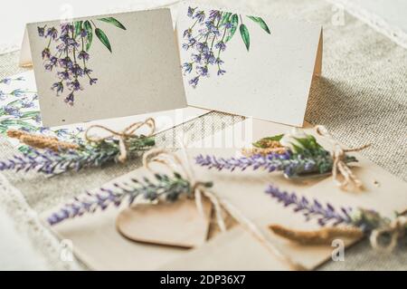 cartoncini per la scrittura di nomi vuoti, busta sul tavolo con fiore di lavanda Foto Stock