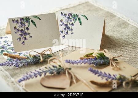 cartoncini per la scrittura di nomi vuoti, busta sul tavolo con fiore di lavanda Foto Stock