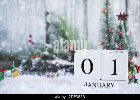 Capodanno. Blocchi di calendario in legno bianco con la data 1 gennaio e decorazioni natalizie con neve. Messa a fuoco selettiva con sfondo sfocato. Foto Stock