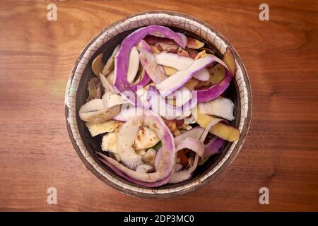 Torniera e bucce di sedano domestiche in una pentola di ceramica sopra Un tavolo di legno ruvido in attesa di essere gettato nel Bidone composto Foto Stock