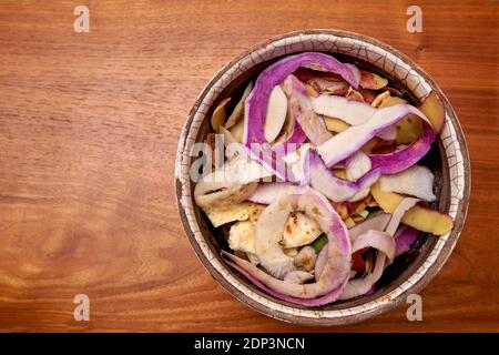 Torniera e bucce di sedano domestiche in una pentola di ceramica sopra Un tavolo di legno ruvido in attesa di essere gettato nel Bidone composto Foto Stock