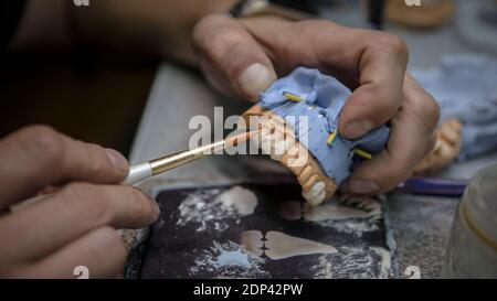 Tecnico dentale, dentature su un mock-up, denti che fanno. Modello di intonaco dei denti su un tavolo da lavoro,un tecnico dentistico fa una protesi Foto Stock