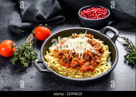 Pasta bolognese, risone con manzo macinato in un piatto. Sfondo nero. Vista dall'alto. Foto Stock