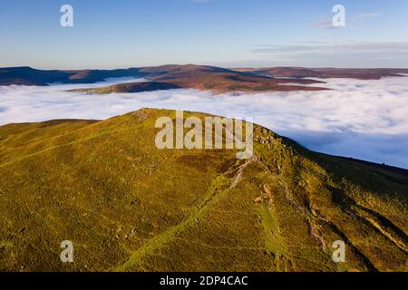 Vista aerea di una cima di montagna che si erge sopra un mare di bassa nube e nebbia nella valle sottostante (Pan di zucchero, Brecon Beacons, Galles) Foto Stock