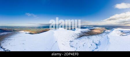 Vista aerea delle bellissime cime innevate che si innalzano sopra una valle profonda in una giornata di sole Foto Stock