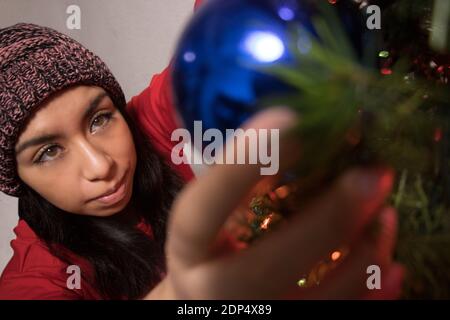 Ragazza latina che decora l'albero di Natale Foto Stock