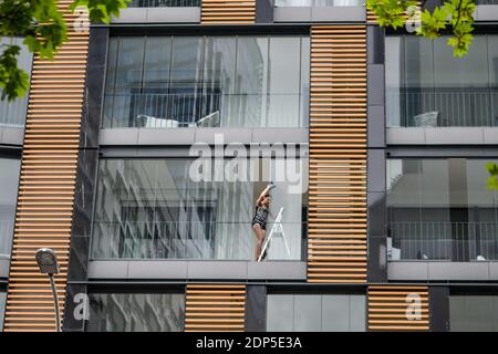 POLONIA - 04 MAGGIO 2020: La ragazza lava le finestre dell'appartamento Foto Stock